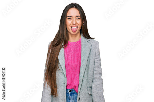 Young hispanic girl wearing business clothes sticking tongue out happy with funny expression. emotion concept.