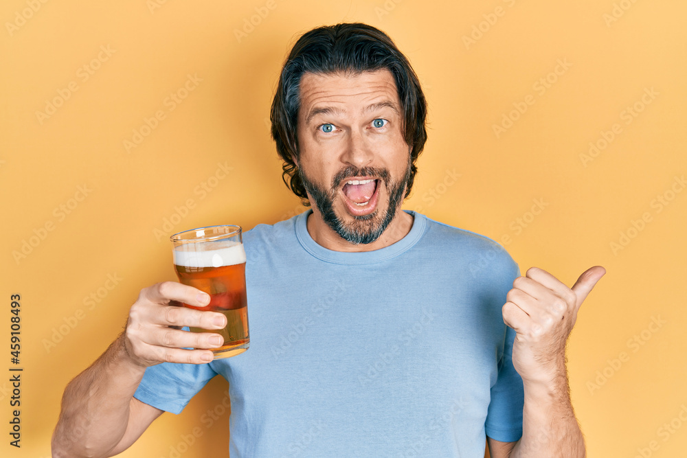 Middle age caucasian man drinking a pint of beer pointing thumb up to the side smiling happy with open mouth Middle age caucasian man drinking a pint of beer pointing thumb up to the side smiling happy with open mouth