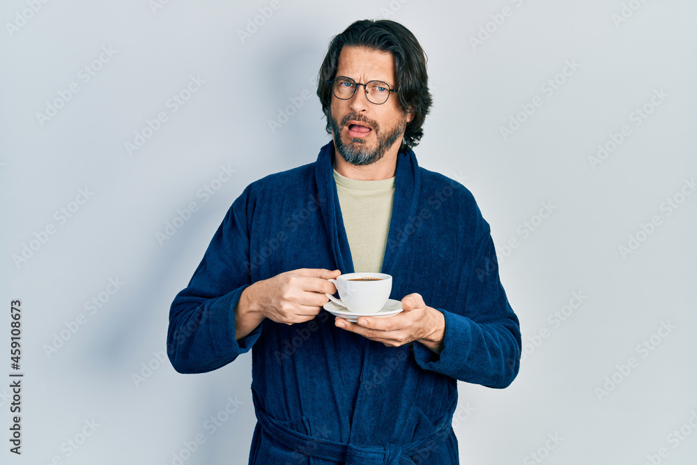 Middle age caucasian man wearing robe drinking coffee in shock face, looking skeptical and sarcastic, surprised with open mouth Middle age caucasian man wearing robe drinking coffee in shock face, looking skeptical and sarcastic, surprised with open mouth