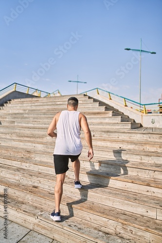 Fototapeta Naklejka Na Ścianę i Meble -  Hispanic sports man working out going upstairs outdoors on a sunny day