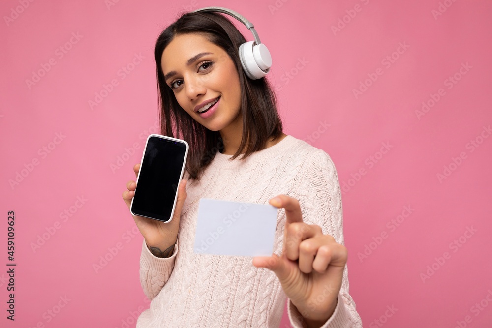 Attractive positive smiling young woman wearing stylish casual outfit isolated on colourful background wall holding credit card and showing mobile phone with empty screen for cutout wearing white Attractive positive smiling young woman wearing stylish casual outfit isolated on colourful background wall holding credit card and showing mobile phone with empty screen for cutout wearing white