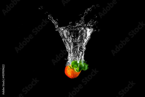 Strawberry splash in the water against black background