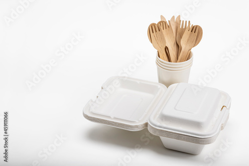 Wooden spoon and fork with knives and bagasse food box , disposable tableware on white background. Eco-friendly materials