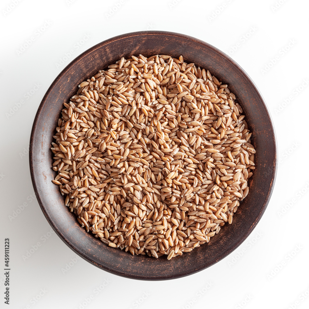 Grains of spelt in ceramic bowl isolated on white background wiht clipping path