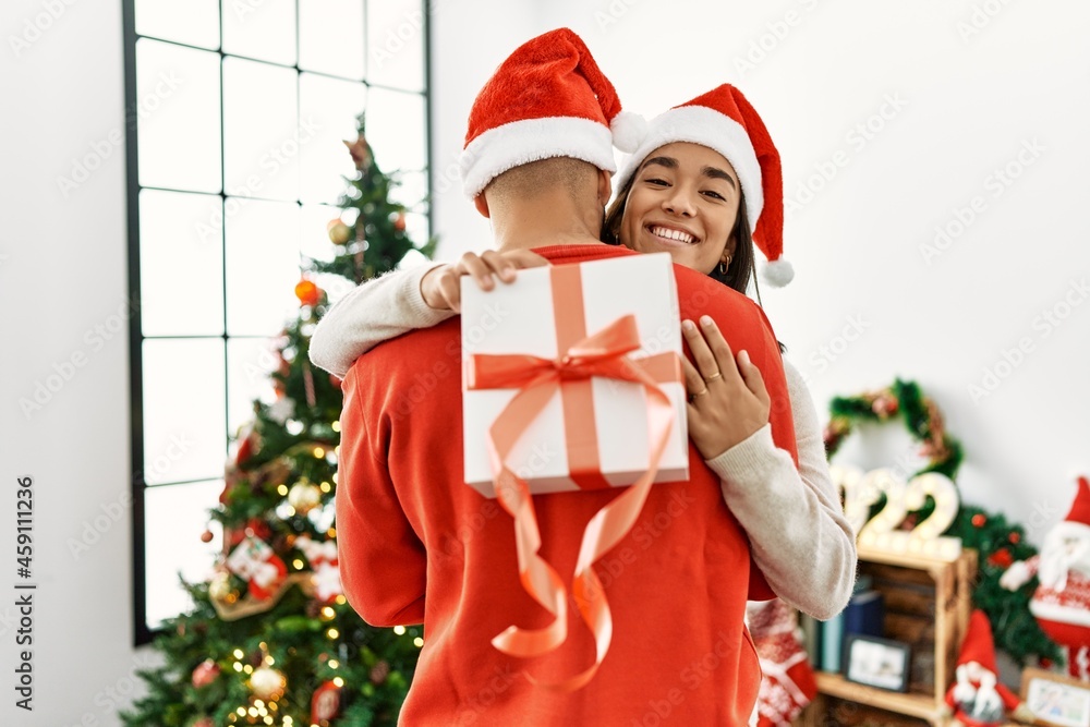 Young latin couple smiling happy and hugging holding christmas gift at home. Young latin couple smiling happy and hugging holding christmas gift at home.