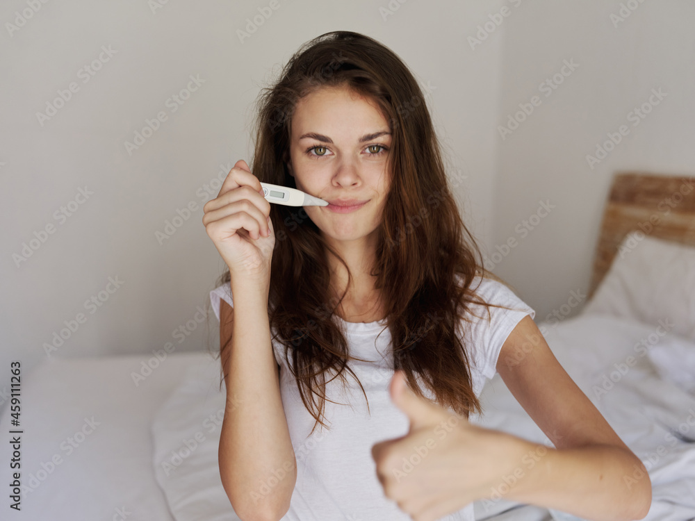 woman with a thermometer in her mouth positive temperature woman with a thermometer in her mouth positive temperature