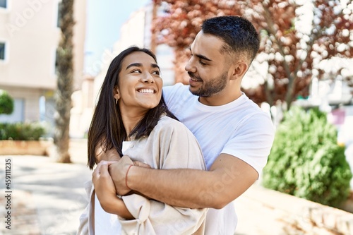 Young latin couple smiling happy and hugging at the city.