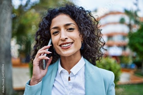 Young hispanic business woman wearing professional look smiling confident at the city speaking on the phone