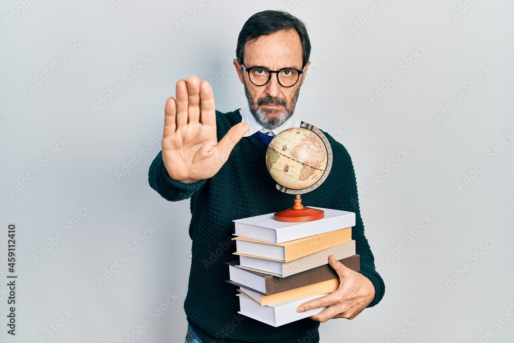 Middle age hispanic man graduated on geography with open hand doing stop sign with serious and confident expression, defense gesture Middle age hispanic man graduated on geography with open hand doing stop sign with serious and confident expression, defense gesture