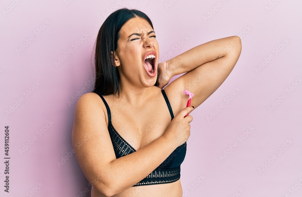 Beautiful brunette woman shaving armpit hair with razor angry and mad  screaming frustrated and furious, shouting with anger. rage and aggressive  concept. Stock Photo | Adobe Stock
