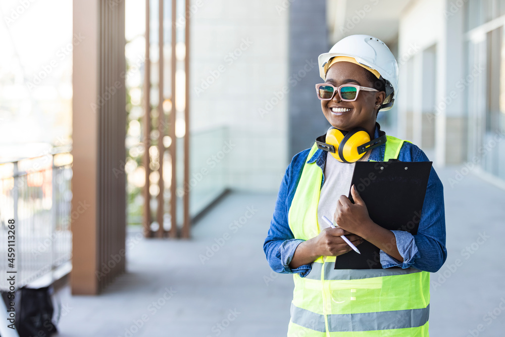 Female construction site engineer. Professional engineer in safety equipment at construction site. Building, developing, construction and architecture concept - smiling woman in white helmet Female construction site engineer. Professional engineer in safety equipment at construction site. Building, developing, construction and architecture concept - smiling woman in white helmet