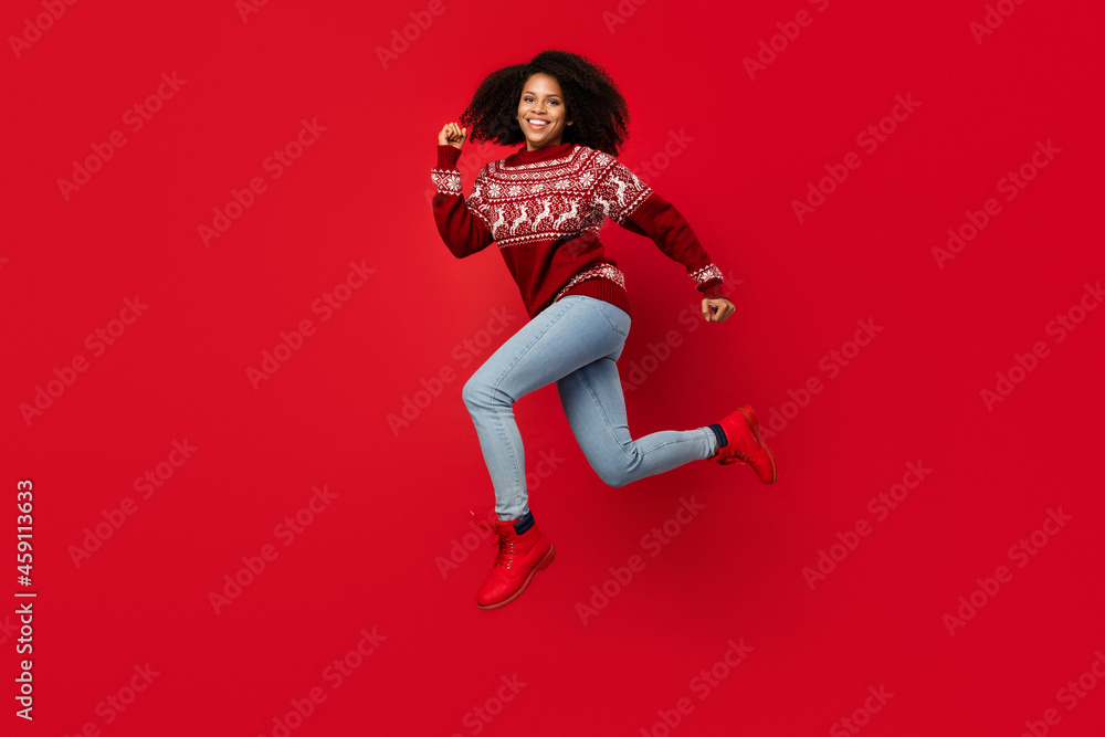 Full length body size photo woman smiling jumping running wearing sweater isolated bright red color background Full length body size photo woman smiling jumping running wearing sweater isolated bright red color background