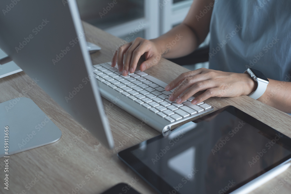 Close up, woman hands typing, working on desktop computer keyboard with digital tablet and mobile phone on table at home office Close up, woman hands typing, working on desktop computer keyboard with digital tablet and mobile phone on table at home office