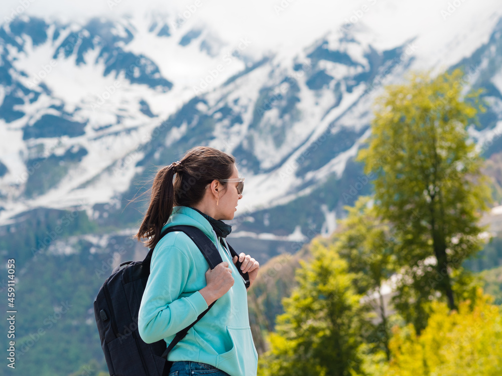 Young female tourist with a backpack on her back hiking in the mountains, Young female tourist with a backpack on her back hiking in the mountains,