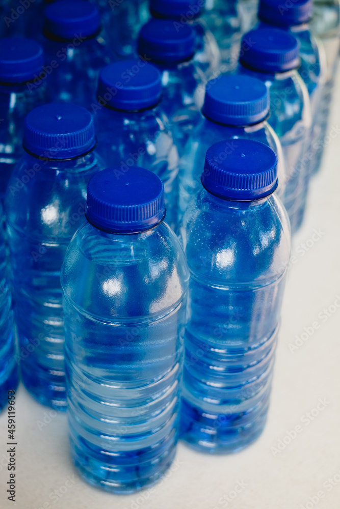 Several lined up drinking bottled water with no label on white table. Selective focus. Several lined up drinking bottled water with no label on white table. Selective focus.
