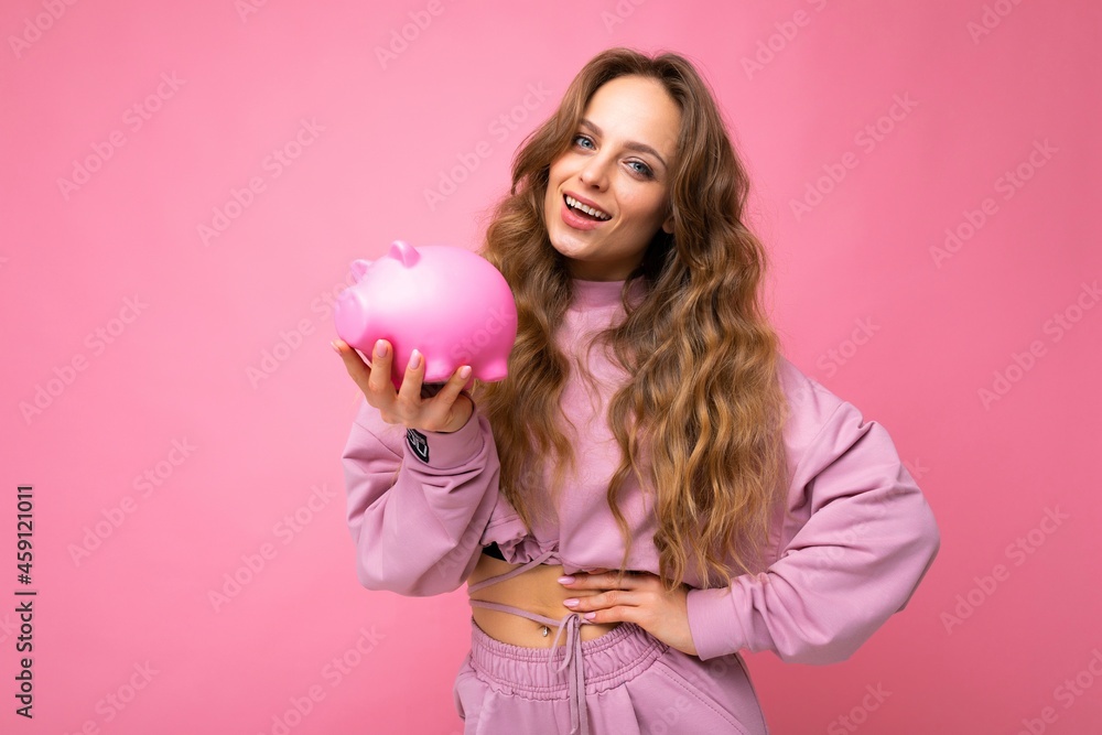 Portrait of happy positive smiling young beautiful attractive woman with wavy long blonde hair with sincere emotions wearing stylish pink hoodie isolated over pink background with copy space and Portrait of happy positive smiling young beautiful attractive woman with wavy long blonde hair with sincere emotions wearing stylish pink hoodie isolated over pink background with copy space and