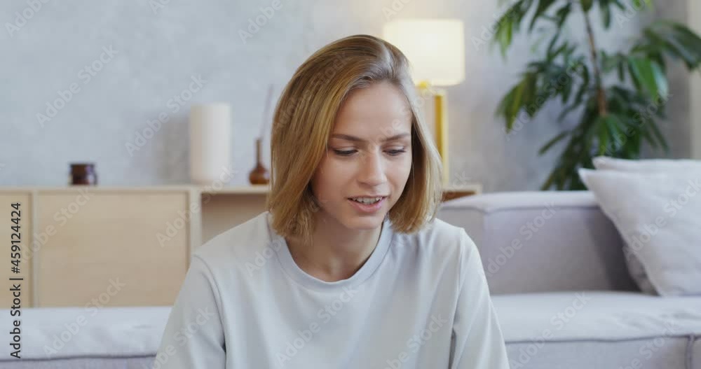 A woman with headphones talking by video call on laptop and drinking from mug A woman with headphones talking by video call on laptop and drinking from mug