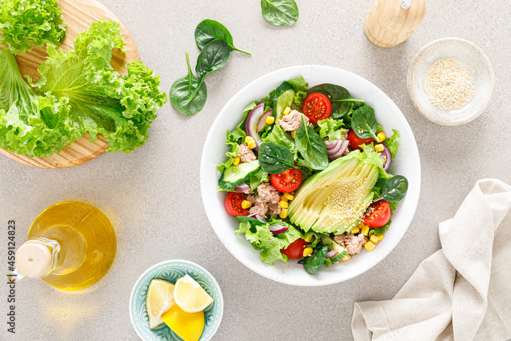 Avocado and tuna fresh vegetable salad with tomato, cucumber corn, onion, lettuce and spinach. Healthy and detox food concept. Ketogenic diet. Buddha bowl dish on light background, top view Avocado and tuna fresh vegetable salad with tomato, cucumber corn, onion, lettuce and spinach. Healthy and detox food concept. Ketogenic diet. Buddha bowl dish on light background, top view