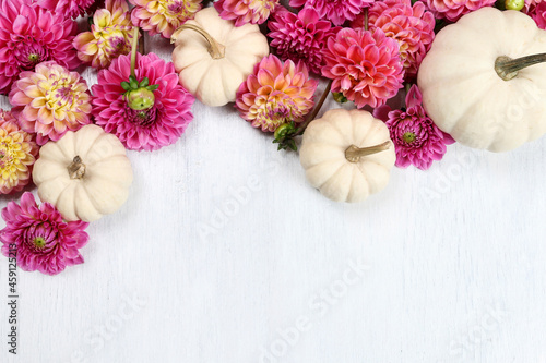Colorful dahlia flowers and white baby boo pumpkin on wooden background.
