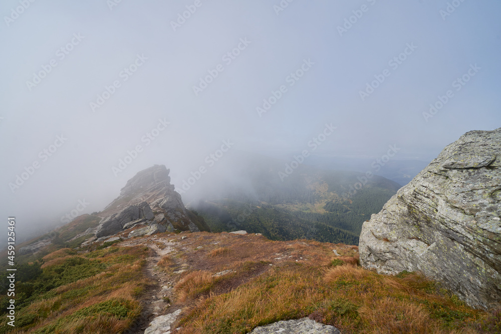 Big stones on a mountain range in clouds. Fog in the mountains.  Wild nature background