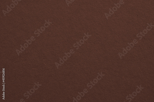 The surface of brown cardboard. Paper texture with cellulose fibers. Cafe noir color background. Dark paperboard wallpaper. Textured graceful classic backdrop. Top-down. Macro