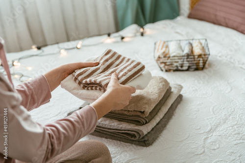 Woman folding clothes in bedroom, organizing laundry in boxes and baskets. Concept of minimalism lifestyle and japanese t shirt folding system. Tidy up wardrobe