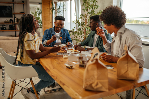 Vászonkép Group of young adults eating take out food at home