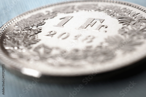 1 Swiss franc coin close-up. Background on the topic of the economy, business, money of Switzerland. Light pale blue and brown backdrop. Banking and the national currency. Macro