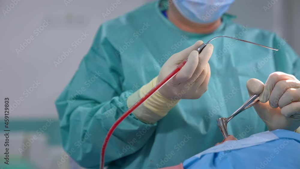 Surgical instruments in doctor's hands. Doctor performs surgical procedure using special medical tools. Nurse assists doctor during operation. Close-up. Surgical instruments in doctor's hands. Doctor performs surgical procedure using special medical tools. Nurse assists doctor during operation. Close-up.