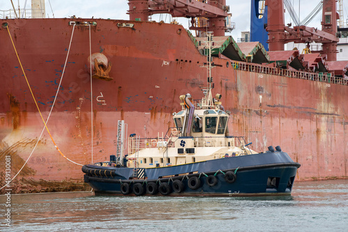 Southampton, England, UK. 2021.  Tug manoeuvres a bulk carrier ship towards her berth in the port of Southampton.