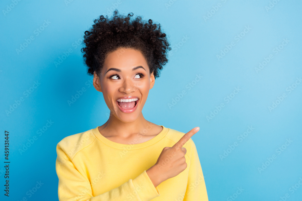 Photo of amazed happy woman point finger look empty space shocked news smile isolated on blue color background Photo of amazed happy woman point finger look empty space shocked news smile isolated on blue color background