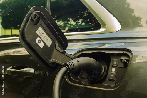 Electric car charging battery at a charger station - close-up of a charging plug in the car