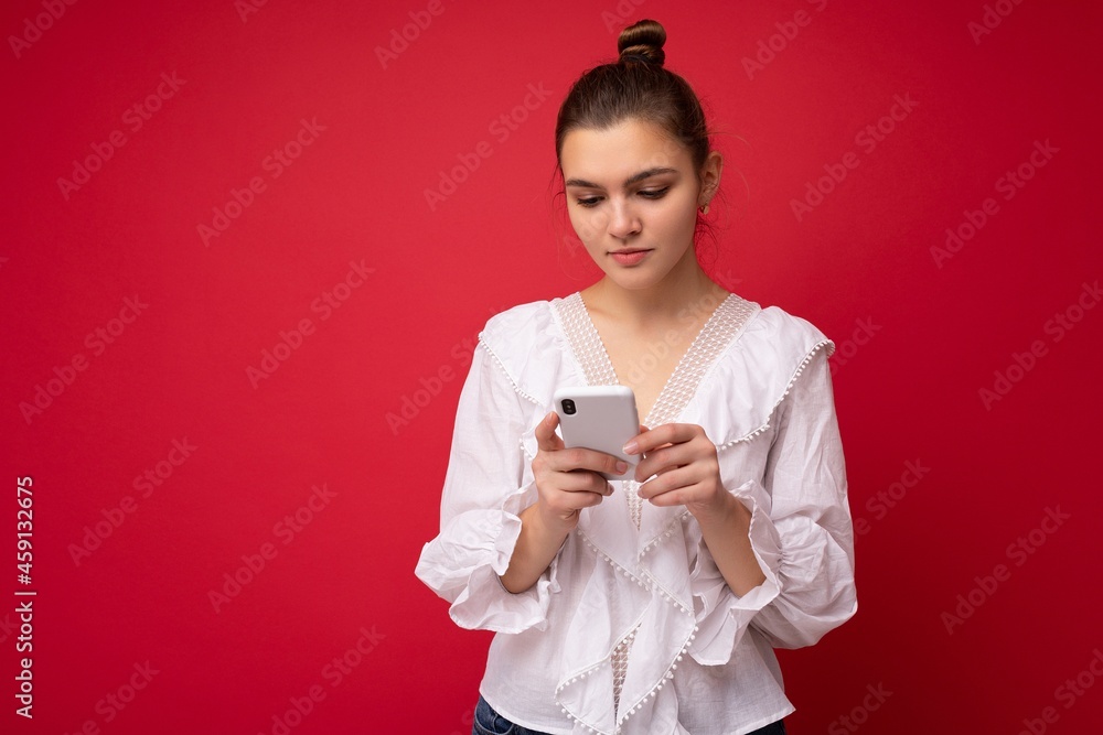 Beautiful young woman wearing casual clothes standing isolated over background surfing on the internet via phone looking at mobile screen Beautiful young woman wearing casual clothes standing isolated over background surfing on the internet via phone looking at mobile screen