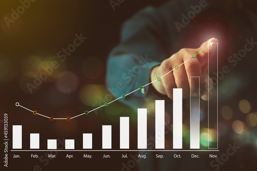 Businessman pointing to a chart showing the highest profitability target for the last month of the year with monthly earnings chart, marketing or finance concepts.