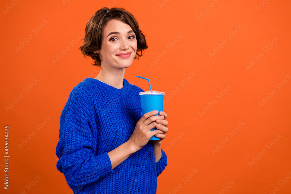 Photo portrait woman smiling drinking fizzy drink isolated vivid orange color background copyspace Photo portrait woman smiling drinking fizzy drink isolated vivid orange color background copyspace