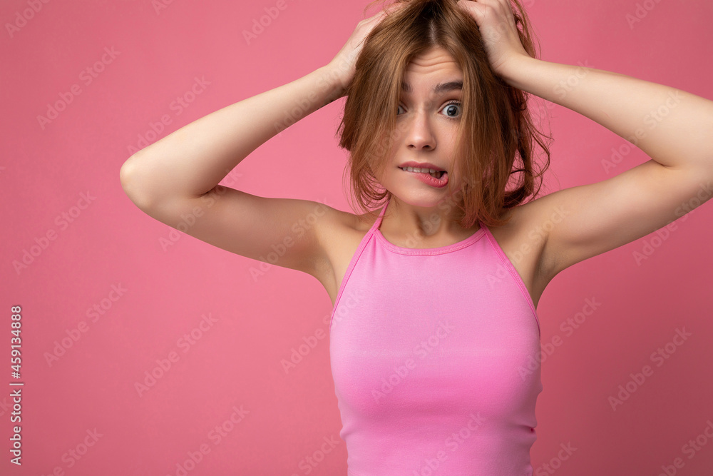 Young emotional beautiful dark blonde female person with sincere emotions isolated on background wall with copy space wearing stylish pink top. Positive concept Young emotional beautiful dark blonde female person with sincere emotions isolated on background wall with copy space wearing stylish pink top. Positive concept
