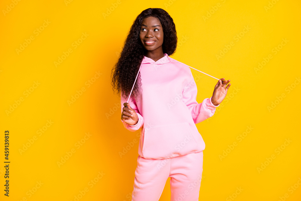Photo of shiny charming dark skin woman dressed pink hoodie looking empty space isolated yellow color background Photo of shiny charming dark skin woman dressed pink hoodie looking empty space isolated yellow color background