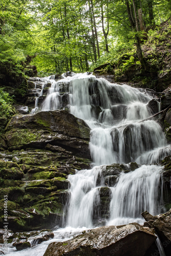 Fototapeta premium View of the waterfall below. Wet stone in the forest covered with green moss