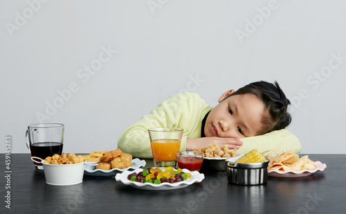 Asian little girl eating and playing indoors by herself