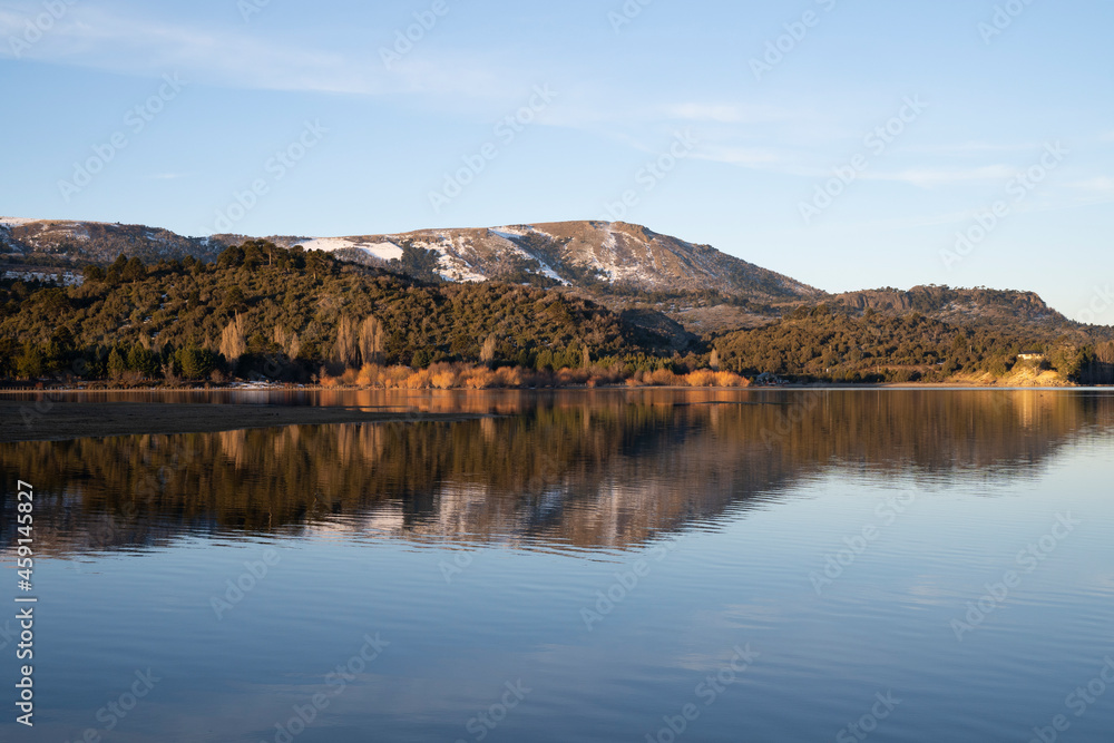 Symmetry in nature. Enchanting view of the Andes mountain range, forest and sky, and the reflection in lake Aluminé water surface at sunset, in Villa Pehuenia, Neuquén, Patagonia Argentina.