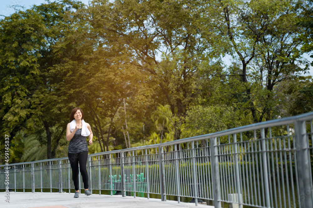 Beautiful Middle-aged Asian woman running in sportswear is smiling happy in park morning. Exercise make body healthy. Workout is health care Good Beautiful Middle-aged Asian woman running in sportswear is smiling happy in park morning. Exercise make body healthy. Workout is health care Good