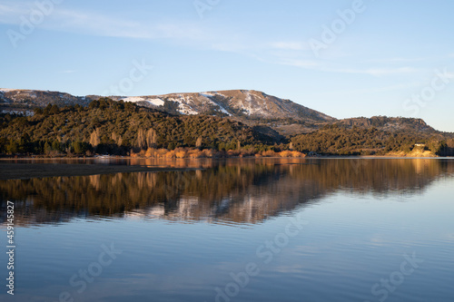 Symmetry in nature. Enchanting view of the Andes mountain range  forest and sky  and the reflection in lake Alumin   water surface at sunset  in Villa Pehuenia  Neuqu  n  Patagonia Argentina.