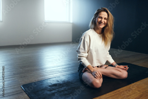 Young woman laughing in lotus position. Yoga practice in the studio. photo