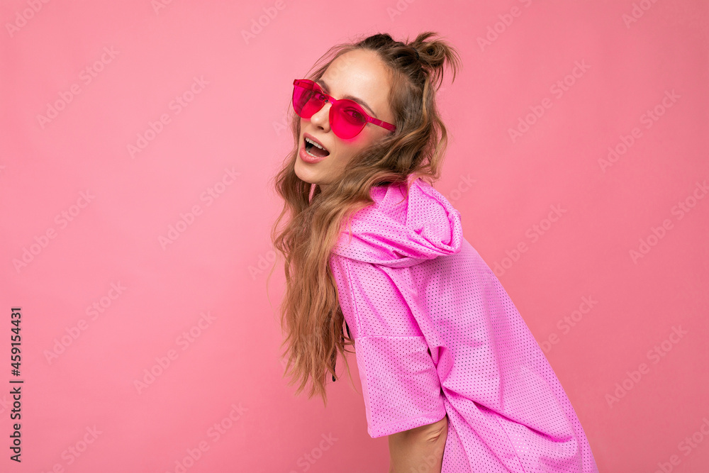 Attractive sexy happy young blonde woman wearing everyday stylish clothes and modern sunglasses isolated on colorful background wall looking at camera Attractive sexy happy young blonde woman wearing everyday stylish clothes and modern sunglasses isolated on colorful background wall looking at camera