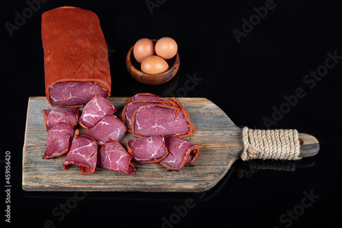 Turkish bacon , pastrami ( kayseri pastirma ). Turkish pastrami on a wooden serving plate. Pastrami is made from the ribeye and beef fillet parts of the cow. photo