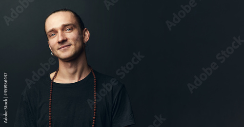 Canvas Print Smiling yogi man with rosary on his neck on black background.
