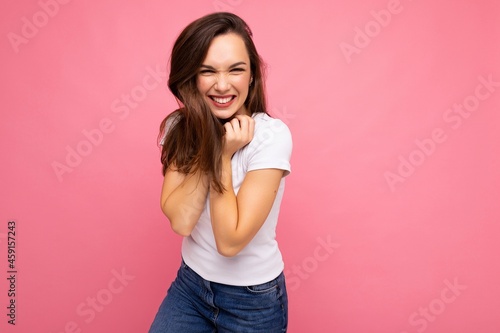 Portrait of positive cheerful fashionable woman in casual t-shirt for mock up isolated on pink background with copy space