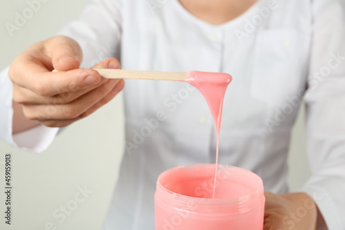 Woman holding spatula with hot depilatory wax, closeup photo