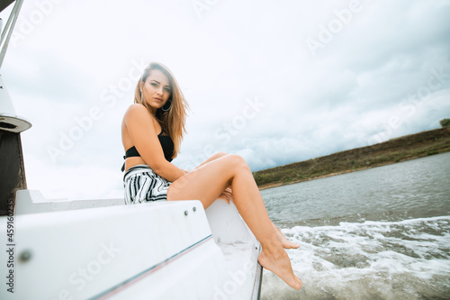 Young beautiful female model on the deck of a yacht at sea. Traveling and yachting concept. Luxury travel on the yacht. Young woman enjoying myself on boat deck sailing the sea.