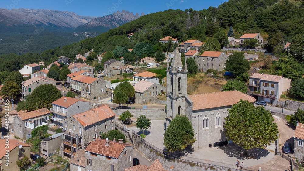 Aerial view of the Parish church of the Assumption in the mountainous village of Zonza in the South of Corsica with the Peaks of Bavella in the background